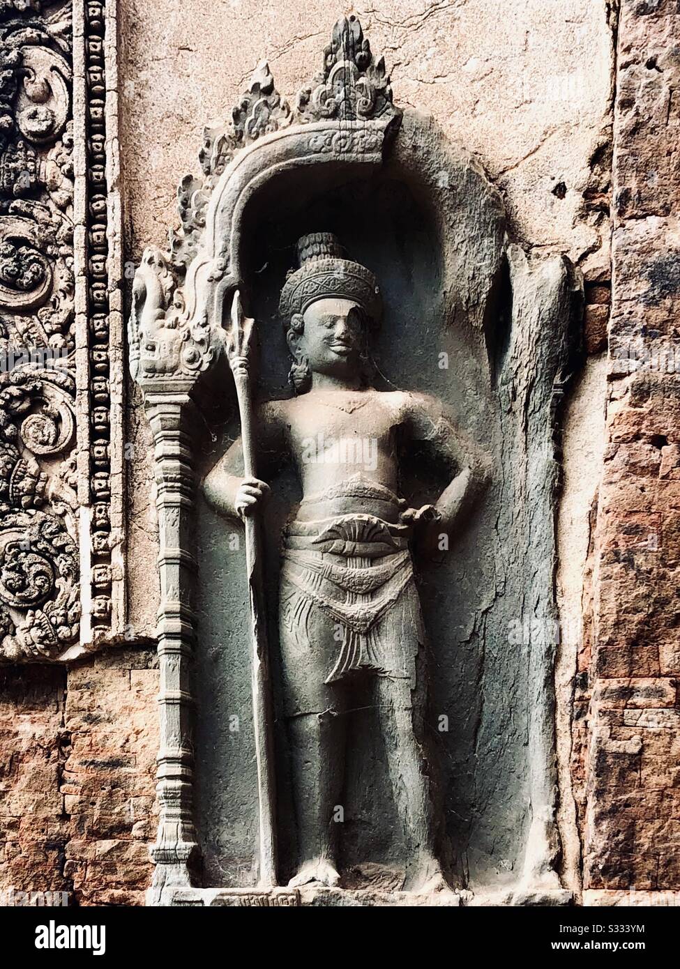 Sculpture of a hindu guardian god holding a trident, Preah Ko temple, Roluos, Cambodia - Smartphone Captured Stock Image