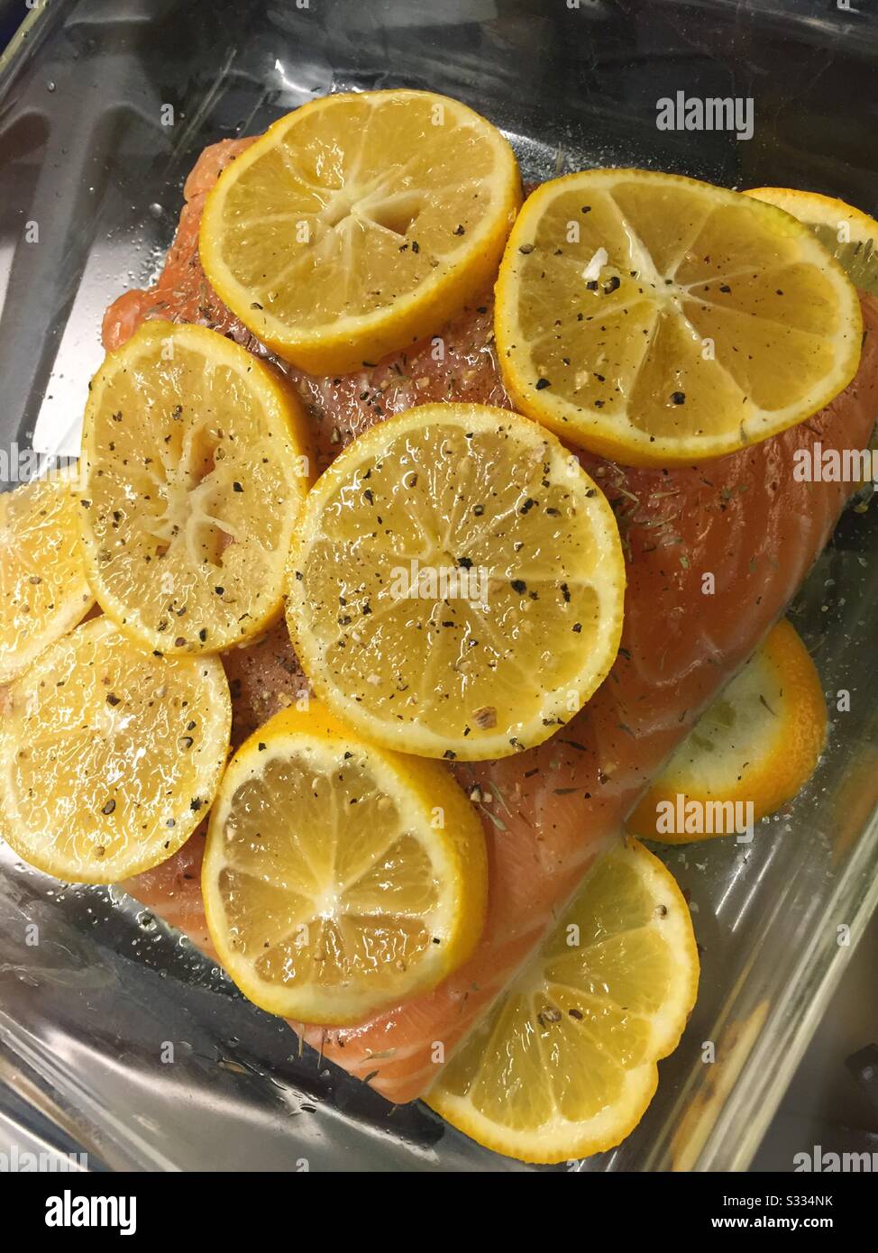 Fresh salmon fillet covered in lemon slices ready to pop into the oven