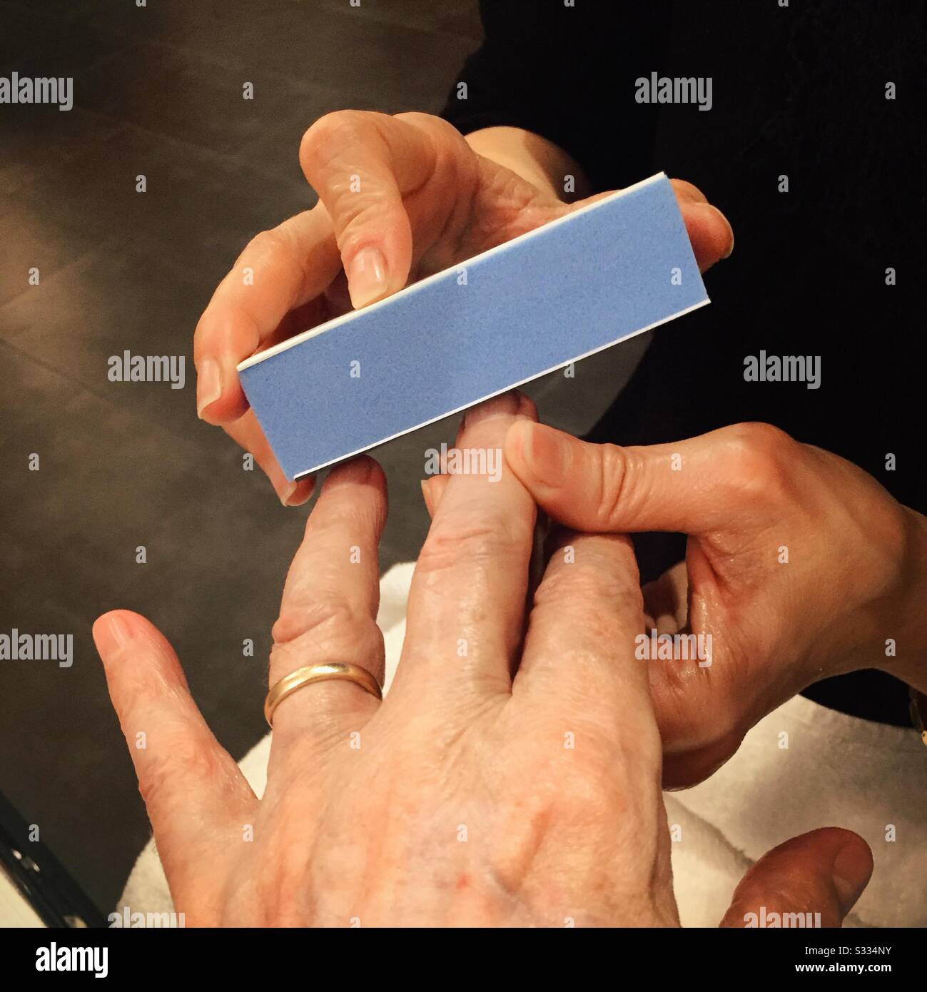 Close up of a married Caucasian male receiving a manicure - Smartphone Captured Stock Image