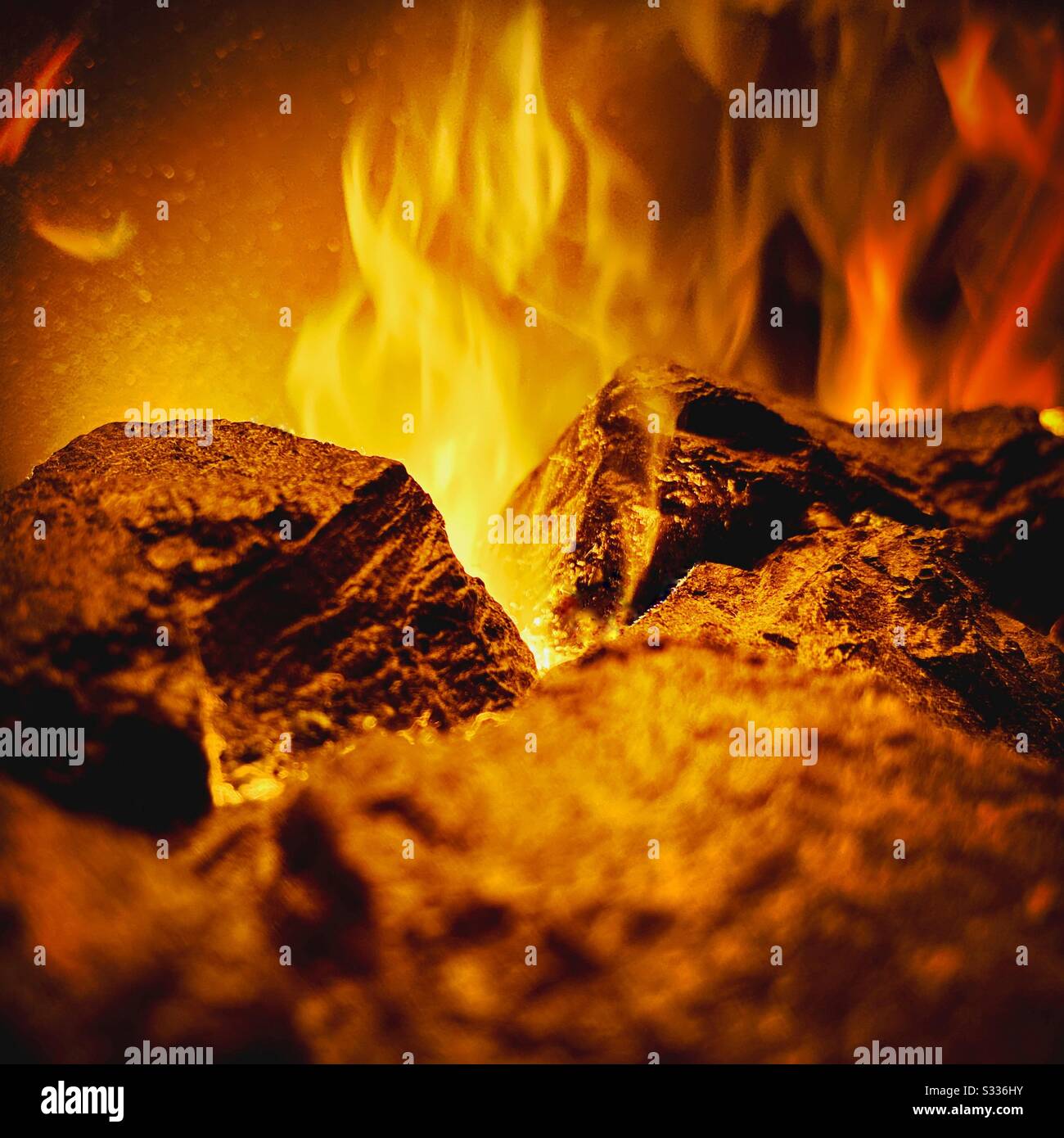 Closeup shot of a flaming coal fireplace with warm orange and yellow rising flames. Flaming fuel romantic atmosphere - Smartphone Captured Stock Image