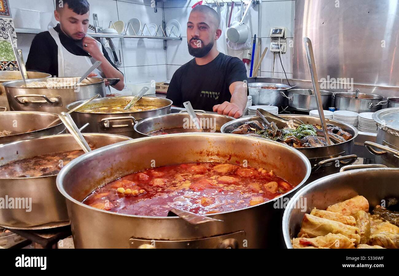 A cook tends to pots of food in the kitchen of the Azura restaurant in Jerusalem's Mahane Yehuda market. - Smartphone Captured Stock Image