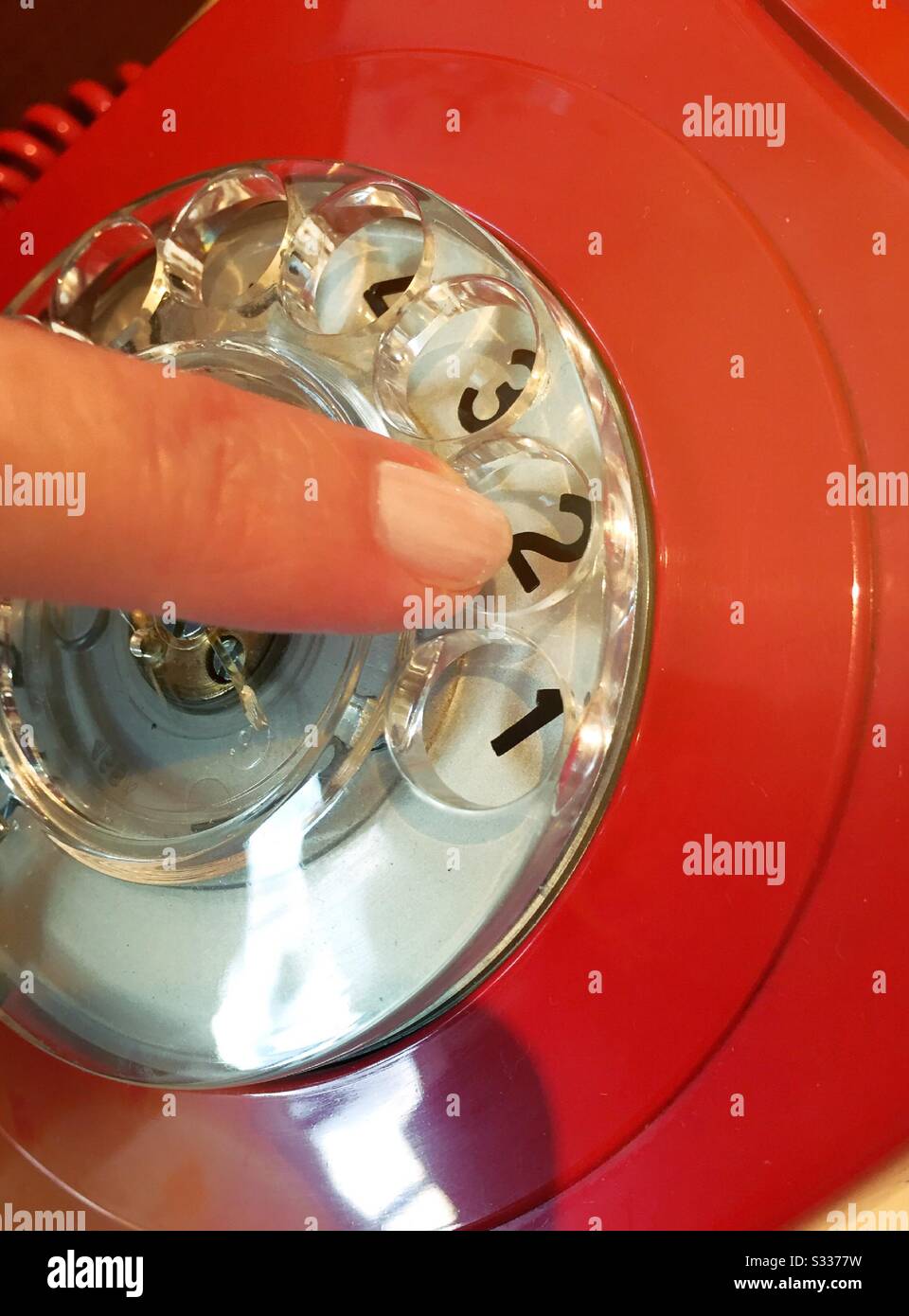 A Caucasian woman dialing an old fashion rotary dial up red telephone, USA - Smartphone Captured Stock Image