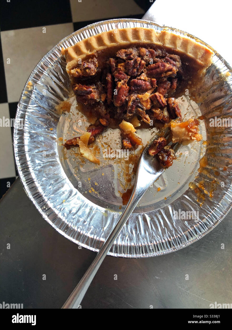 Pecan pie being eaten straight from pie plate in kitchen - Smartphone Captured Stock Image