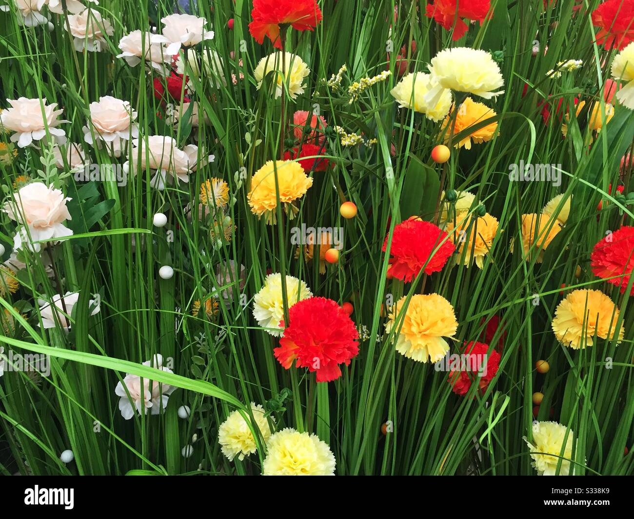 A full frame nature background image of realistic, artificial wild flowers in a colourful garden or meadow with copy space - Smartphone Captured Stock Image