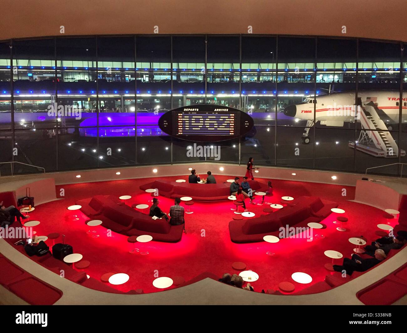 People enjoying the sunken lounge cocktail area in the heart of the TWA hotel at dusk, NYC, JFK airport, United States - Smartphone Captured Stock Image