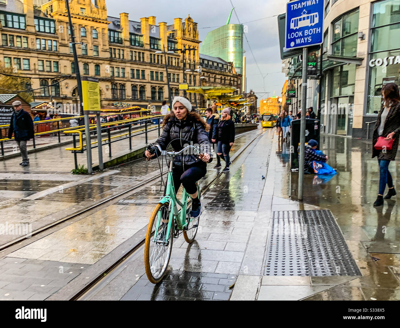 Riding a bicycle past exchange square tram stop in Manchester - Smartphone Captured Stock Image