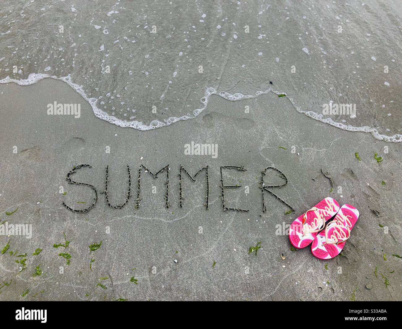 Summer written on sand near a pair of flip flops - Smartphone Captured Stock Image