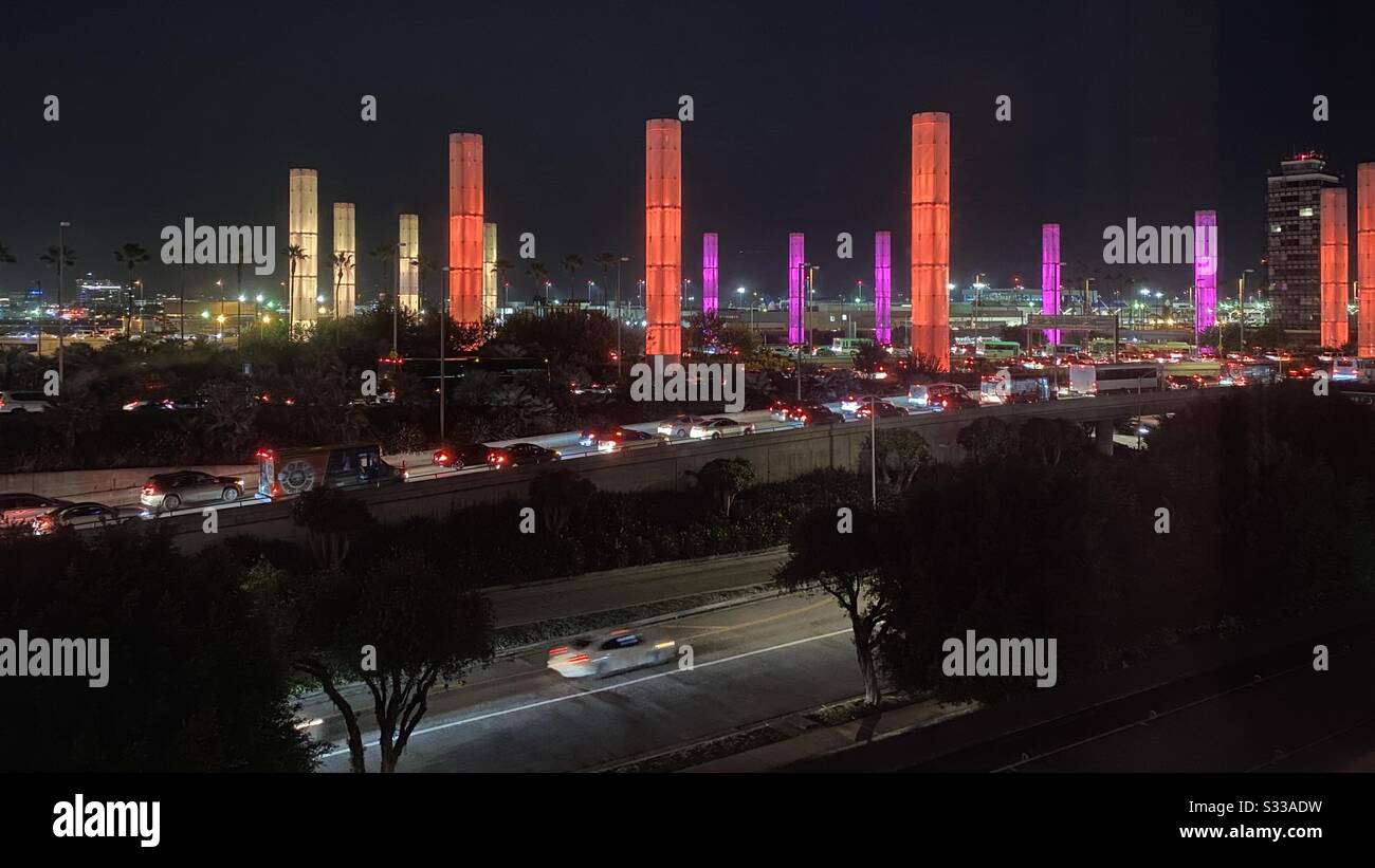 LOS ANGELES, CA, JAN 2020: light columns glowing orange and pink at night, with traffic passing in foreground outside Los Angeles International Airport - Smartphone Captured Stock Image
