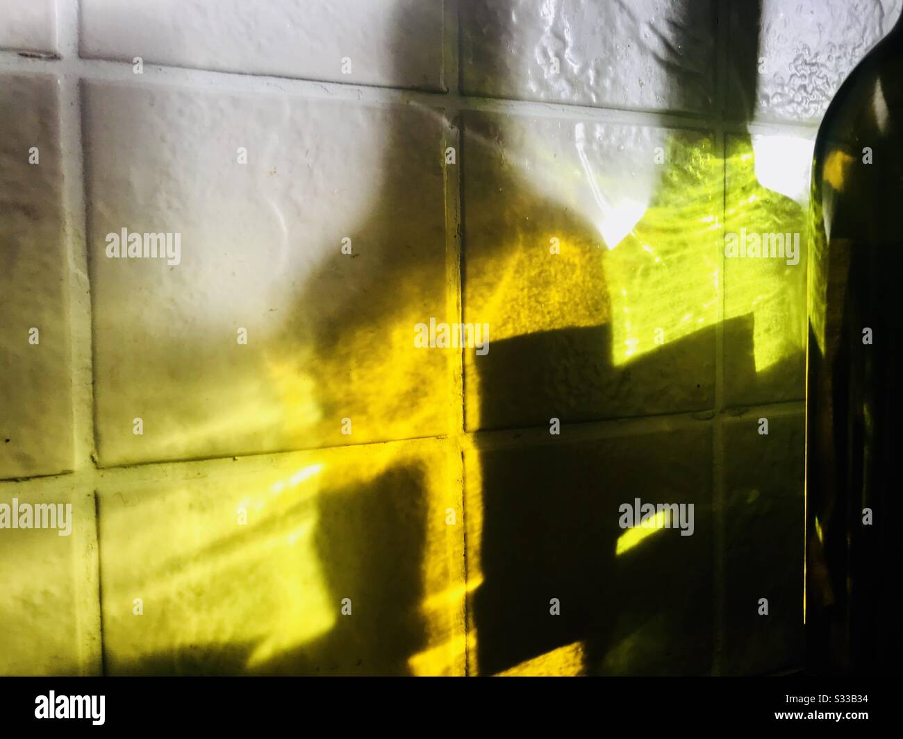 Light shining through wine bottles reflection on tiled wall - Smartphone Captured Stock Image