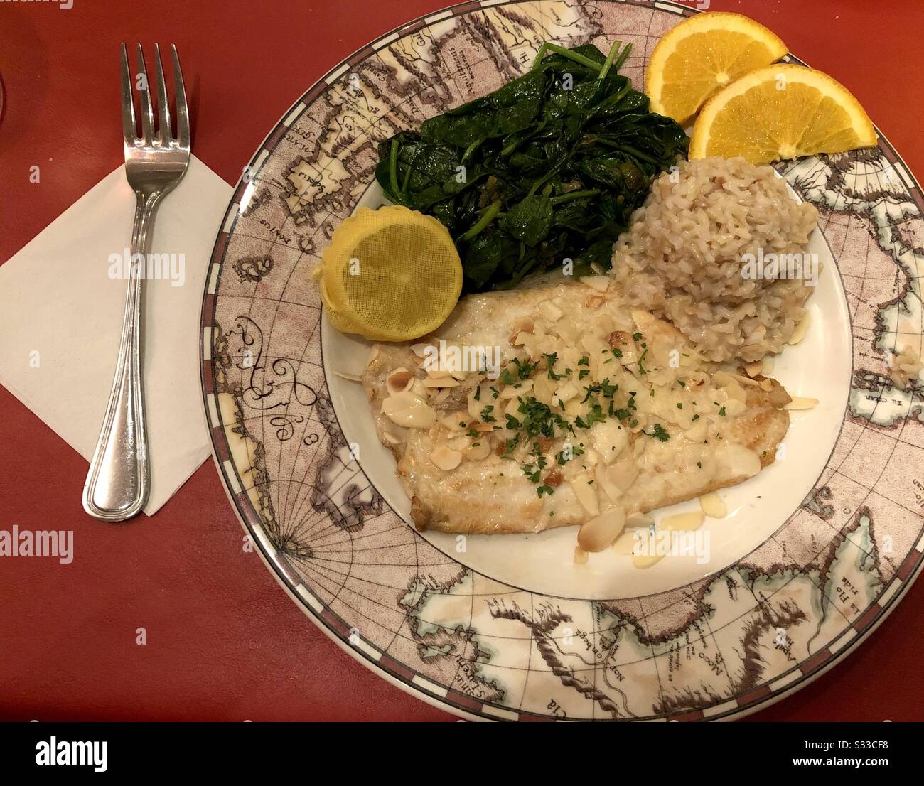 Trout almondine with coconut rice, spinach, lemon and orange garnish. - Smartphone Captured Stock Image