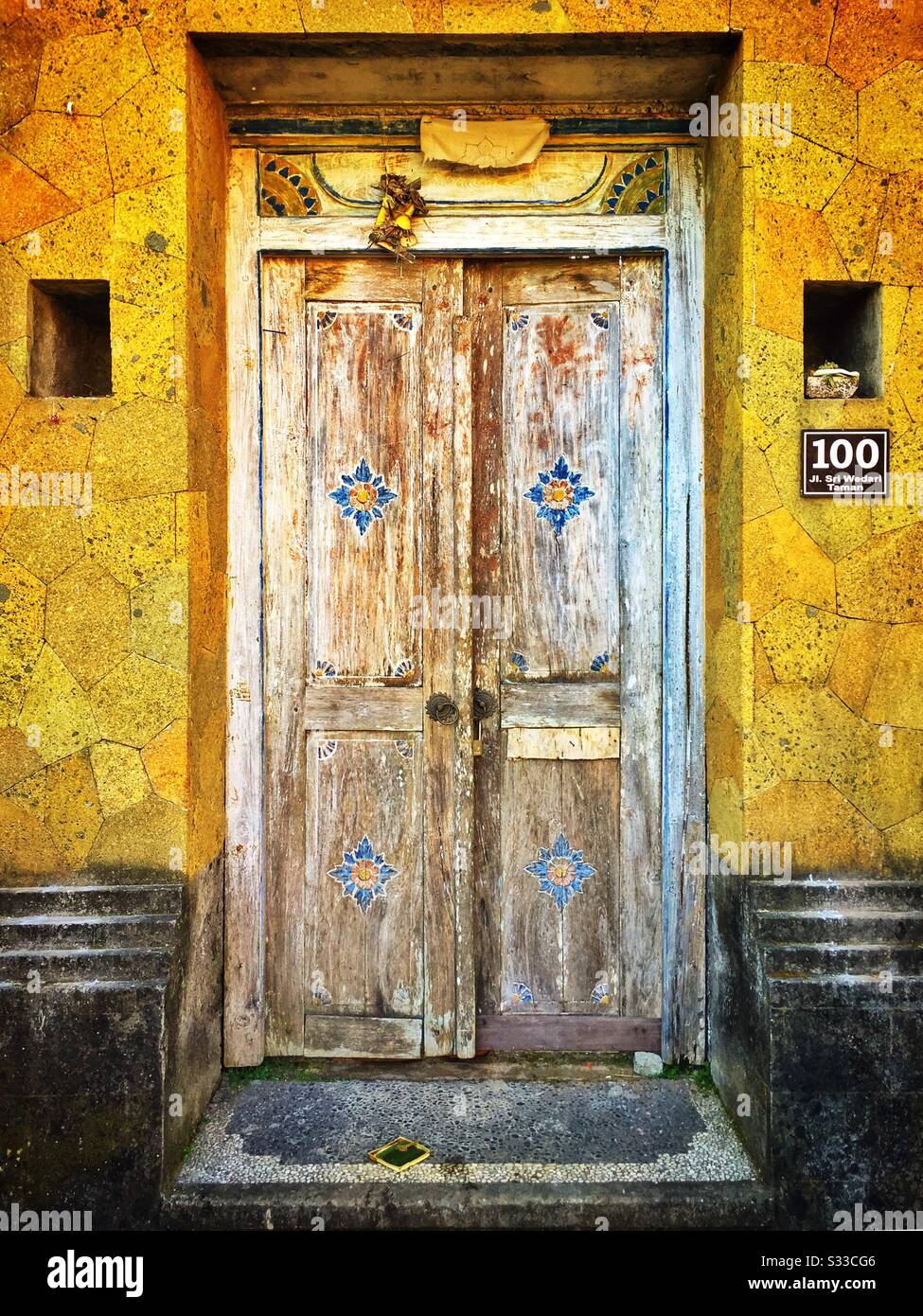 Traditional painted wooden doors form the entrance to a private house in Ubud, Bali, Indonesia - Smartphone Captured Stock Image