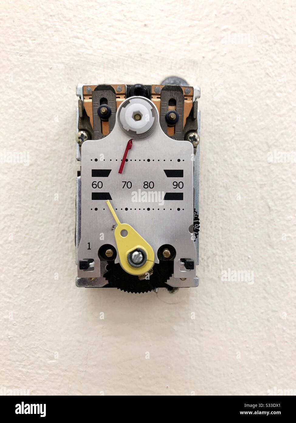 Thermostat in public building with no cover to reveal gears and inner workings - Smartphone Captured Stock Image