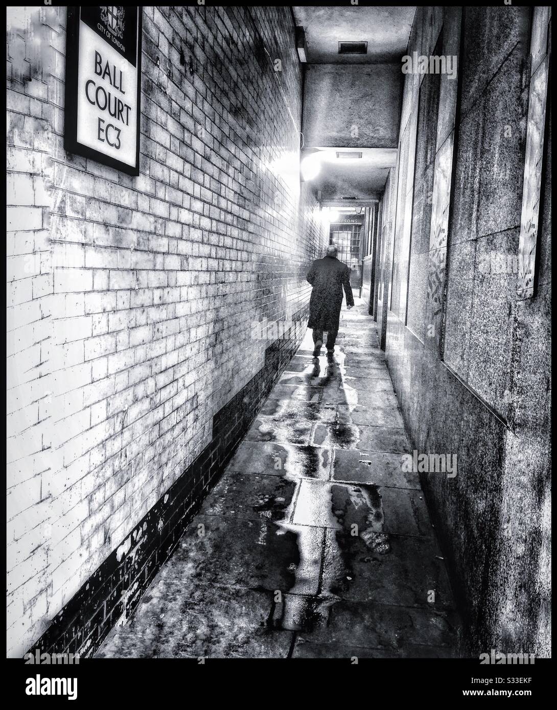 A man walking through an alley way in the city of London. - Smartphone Captured Stock Image
