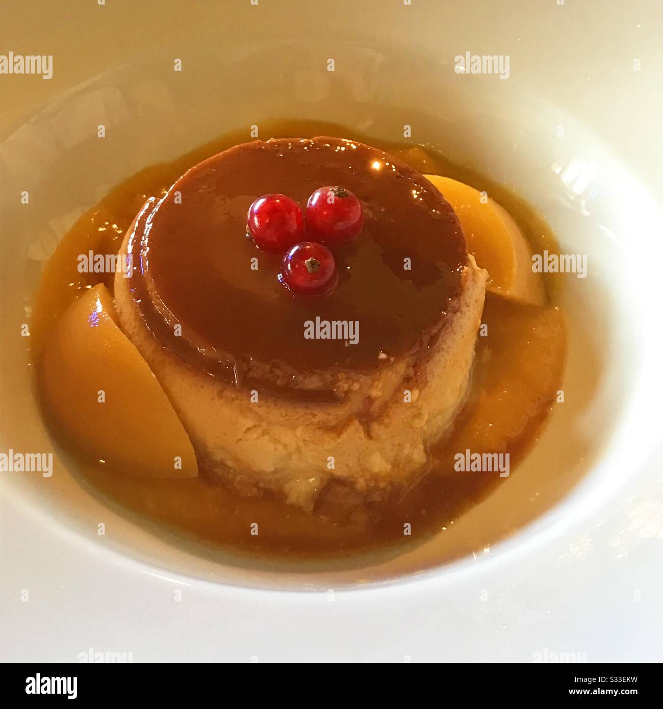 Creme caramel with peach and redcurrants. - Smartphone Captured Stock Image