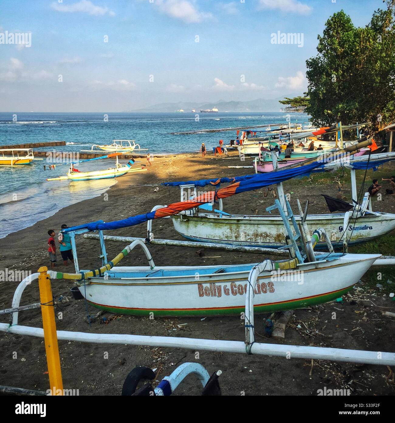 Traditional outrigger fishing boats on the beach at Candidasa, Bali, Indonesia - Smartphone Captured Stock Image
