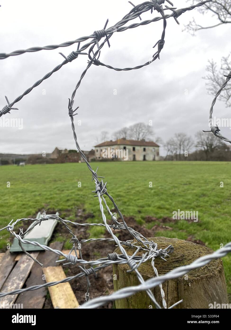 Barbed wire protected ruin of large house Stock Photo