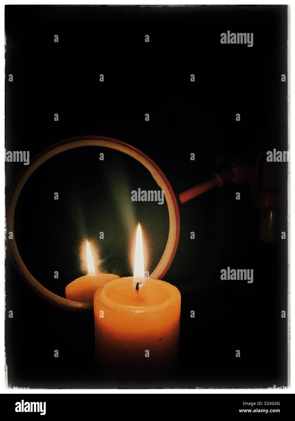 A lit candle in front of a mirror. - Smartphone Captured Stock Image
