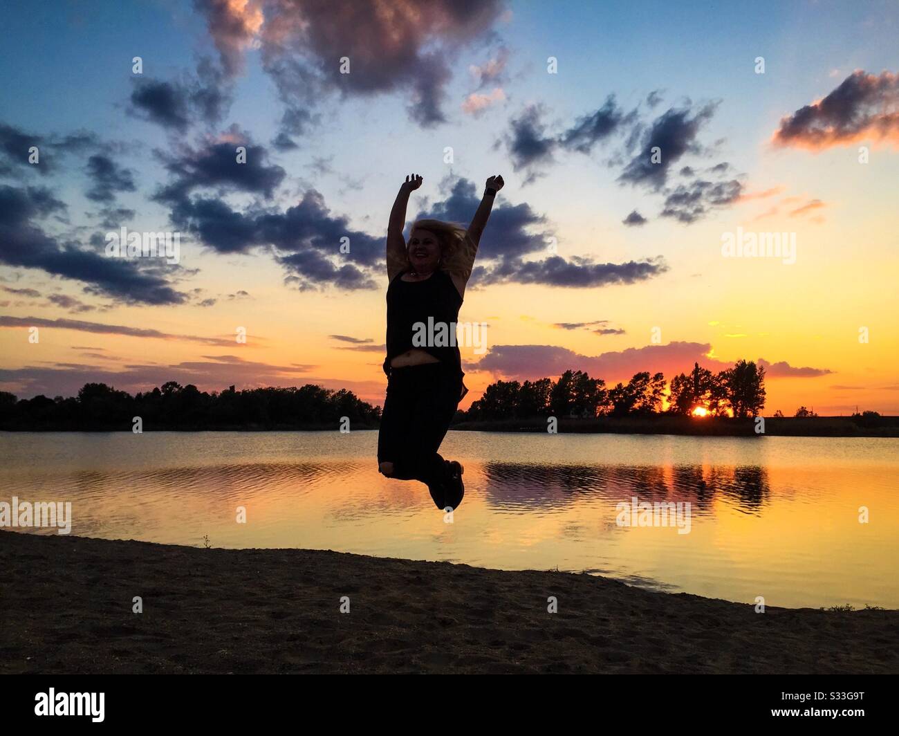 Woman jumping in the air at sunset - Smartphone Captured Stock Image