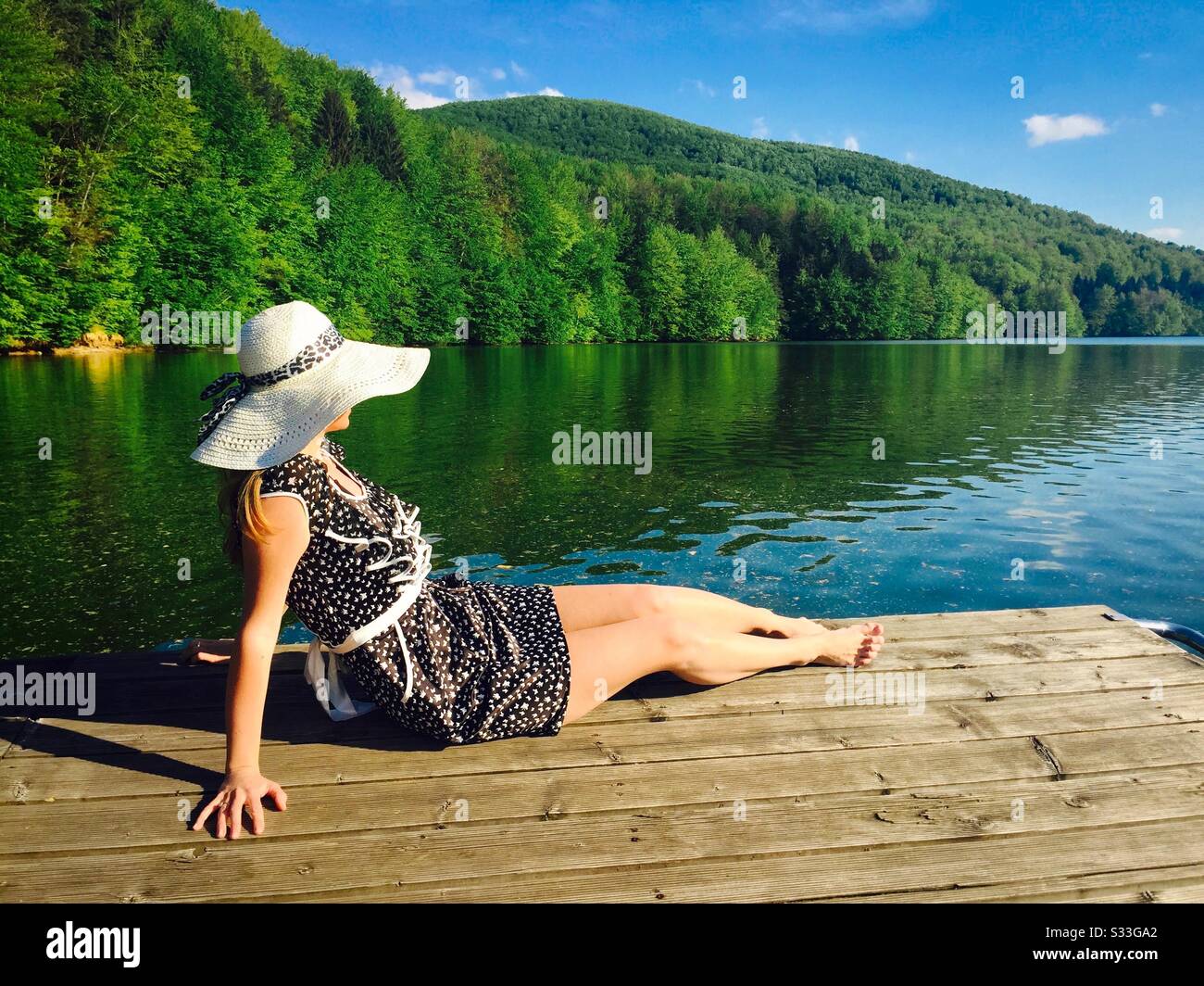 Woman laying on wooden pontoon near the lake in summer - Smartphone Captured Stock Image