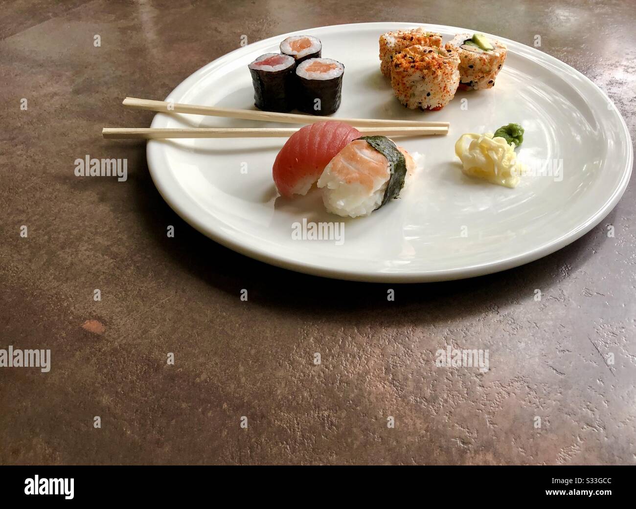 Side angle view of sushi, ginger and wasabi on a white plate with chopsticks - Smartphone Captured Stock Image