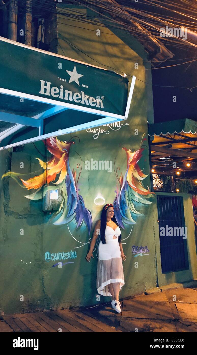 A woman posing in front of an angel wing mural. - Smartphone Captured Stock Image
