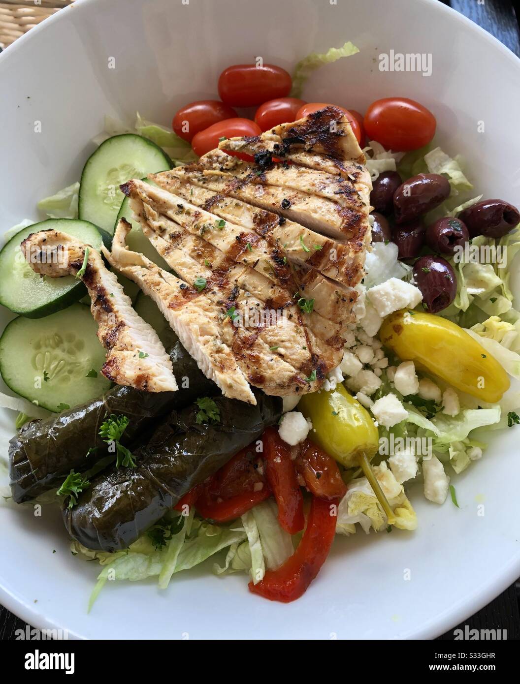 Greek salad with grilled chicken, Grape leaves, Greek olives, green peppers, cucumbers red peppers, tomatoes and feta cheese. - Smartphone Captured Stock Image