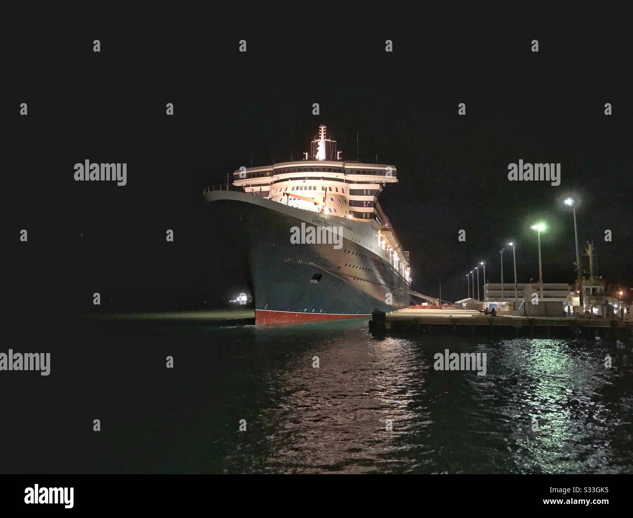 The Queen Mary 2 cruise ship docked at night in Darwin Harbour in the