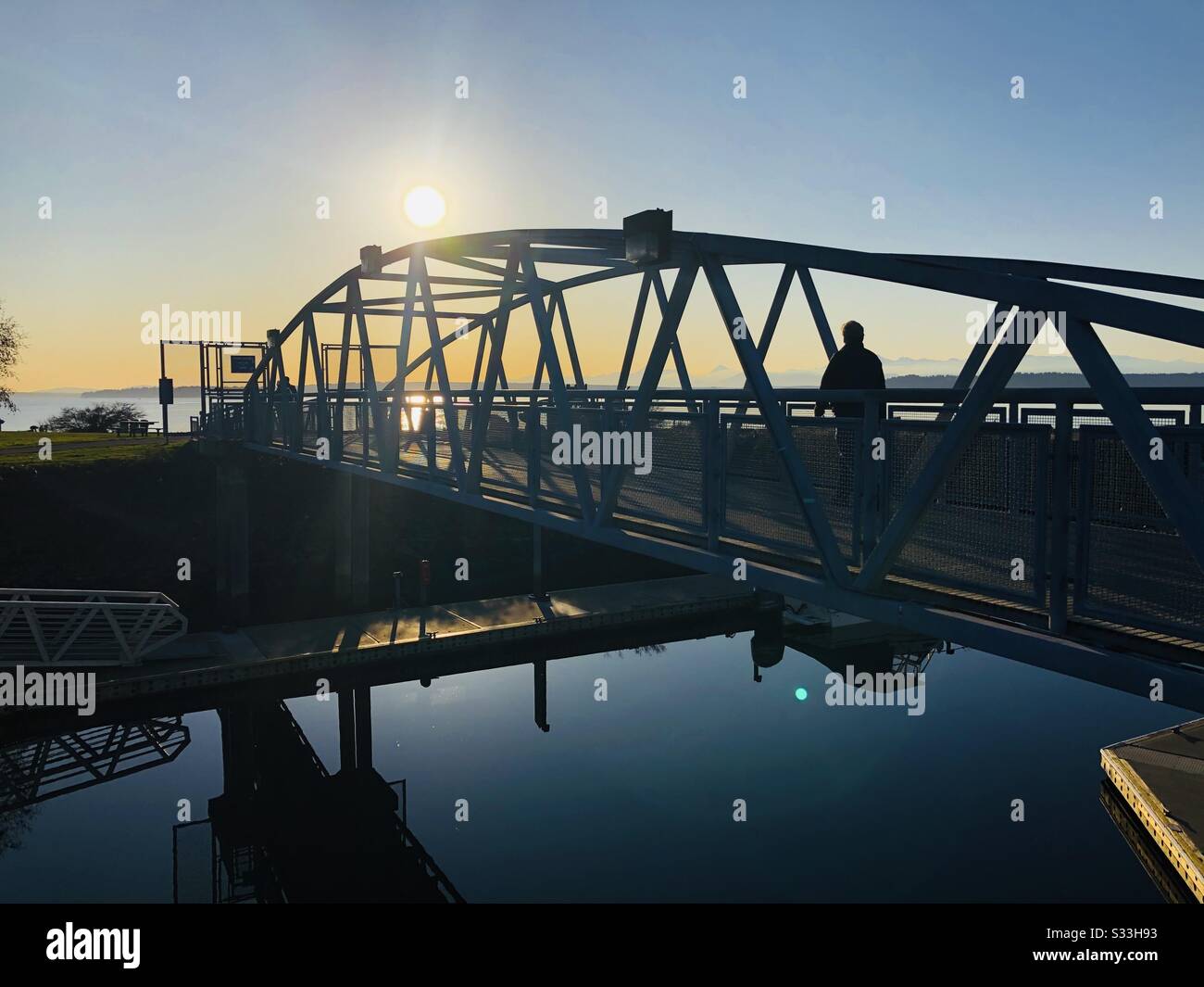 The pedestrian bridge at the Edmonds, WA waterfront from the docks to the dog park on a sunny afternoon with the Salish Sea and the Olympic Mountains in the background. Stock Photo
