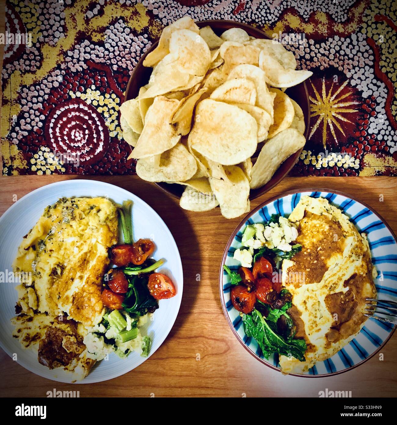 Healthy vegetarian dinner: omelette, nanohana, cherry tomatoes and potato chips Stock Photo