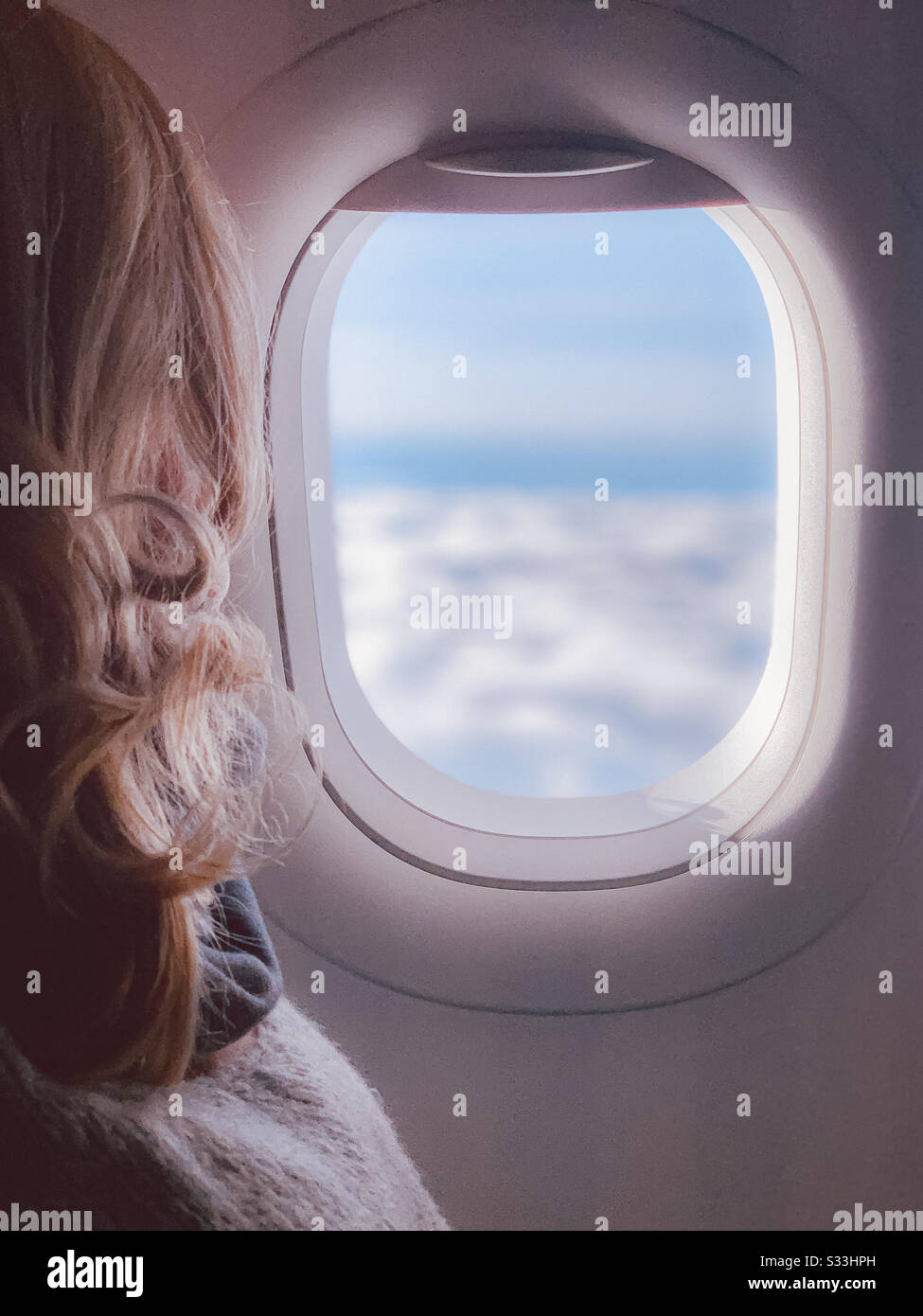 Passenger on a plane looking through the window at the clouds Stock Photo