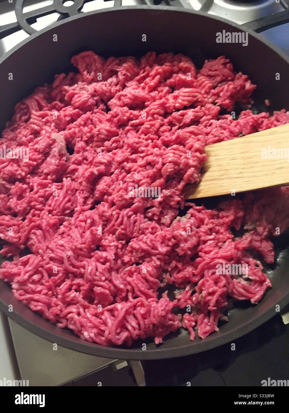 Ground beef being browned and stirred with a large wooden spatula Stock