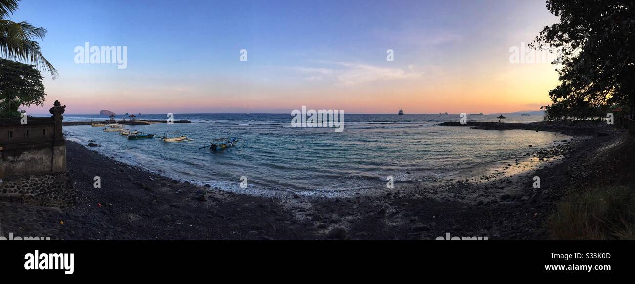 Traditional outrigger fishing boats moored off the beach at sunset, Candidasa, Bali, Indonesia - Smartphone Captured Stock Image