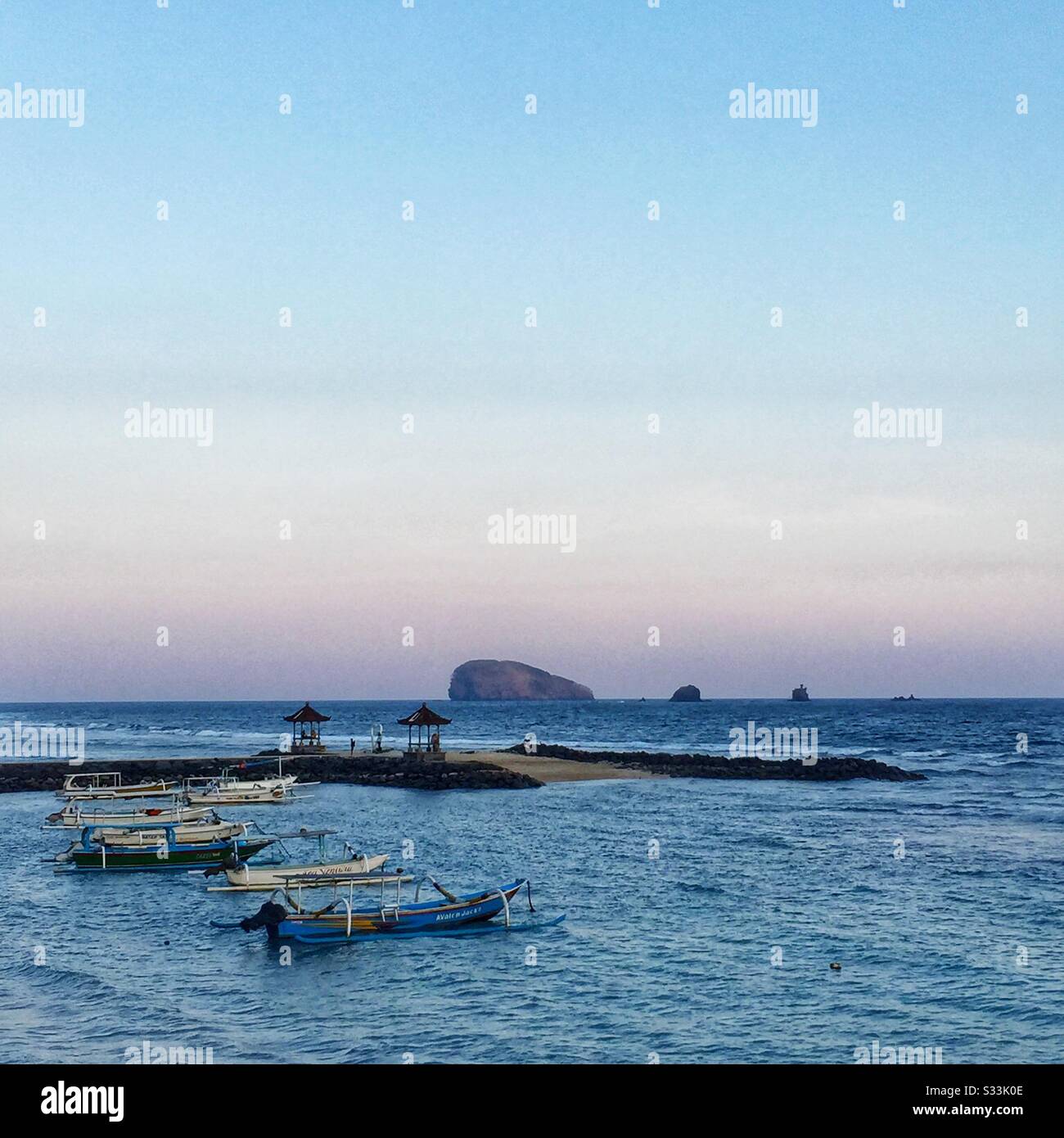 Traditional outrigger fishing boats moored off the beach at sunset, Candidasa, Bali, Indonesia - Smartphone Captured Stock Image