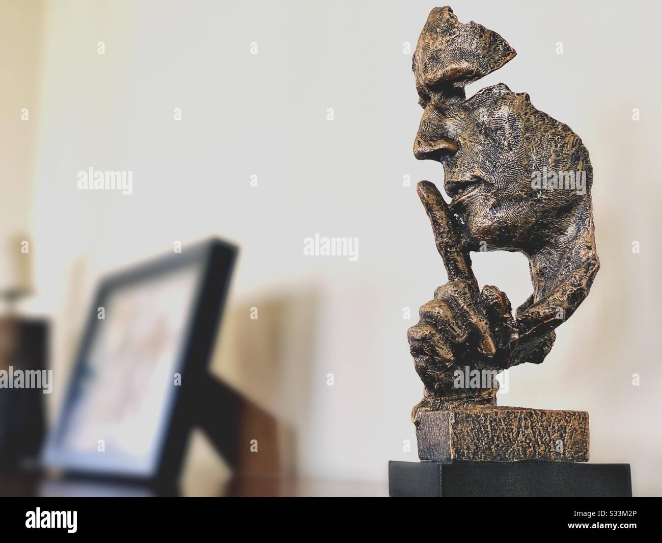 A close up and selective focus shot of an abstract face holding index finger to mouth, indicating silence, quiet, shh, shhh, sh. Modern home decor ornament Stock Photo