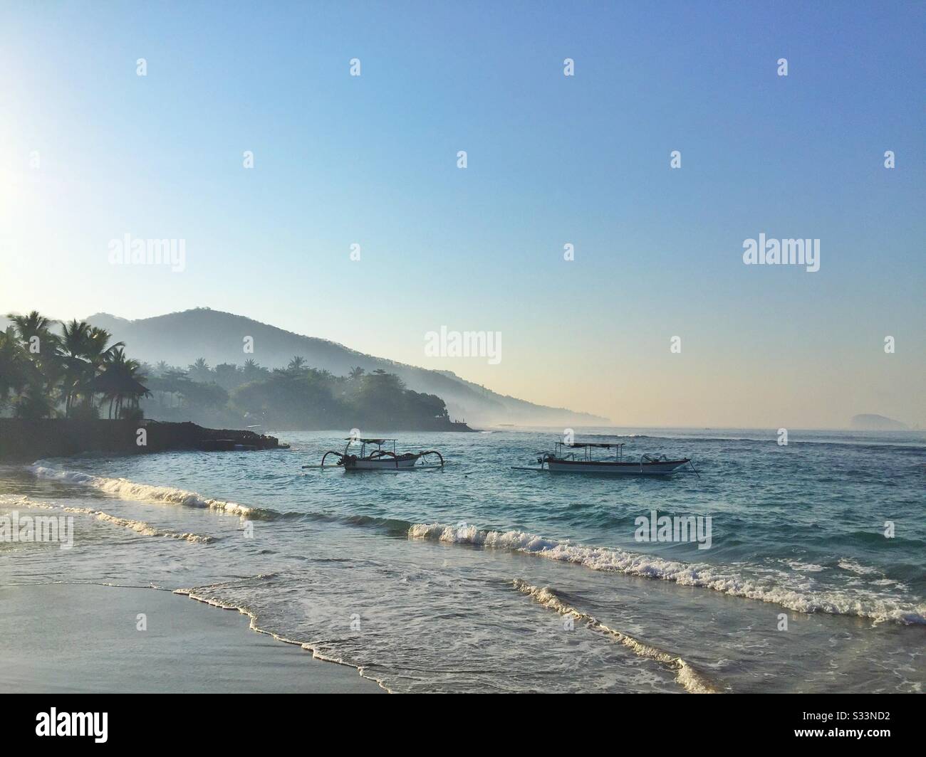 Traditional outrigger fishing boats moored at Pantai Anom (Anom Beach), Candidasa, Bali, Indonesia - Smartphone Captured Stock Image
