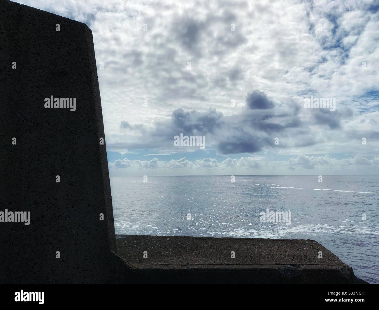 The flat shimmering peaceful ocean reflecting the cloudy sky above , view from the breakwall, Coffs Harbour Australia - Smartphone Captured Stock Image