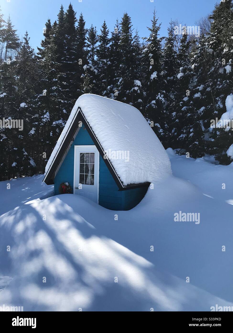 A tiny blue A-frame cabin in Cape Breton, Nova Scotia covered in snow Stock Photo
