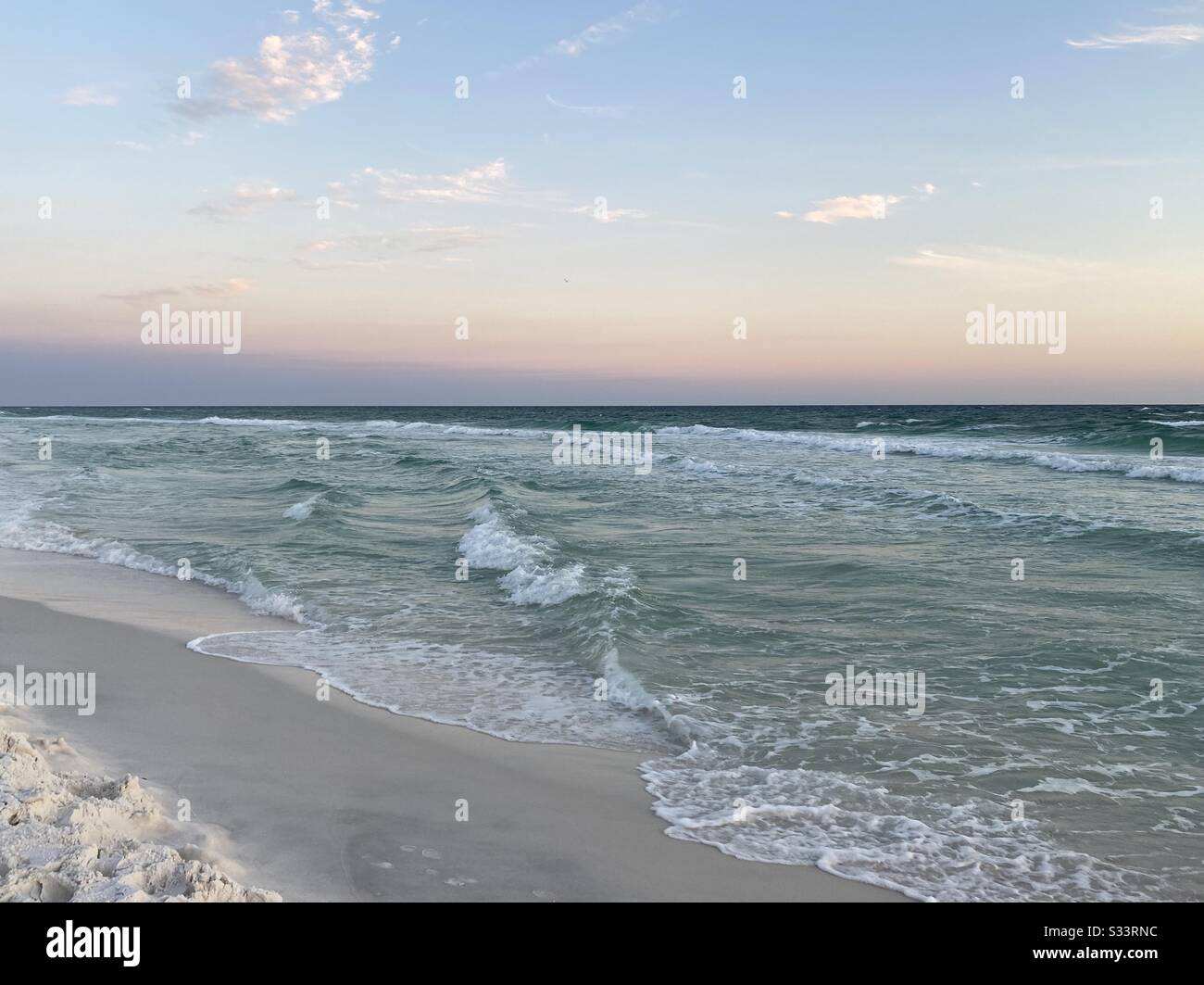 Soft pastel sunset skies over emerald colored water of the Gulf of ...