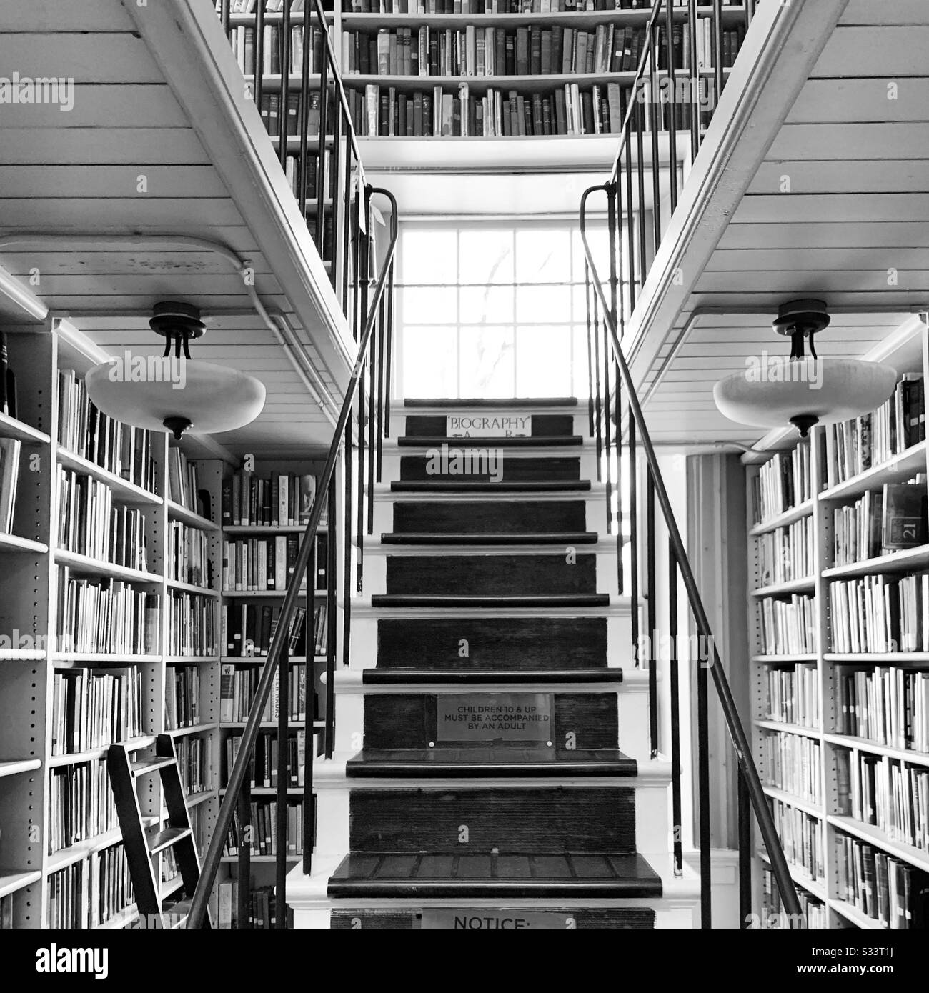 Black and white image of stairs amidst stacks at the Providence Athenaeum, Providence, Rhode Island, United States - Smartphone Captured Stock Image