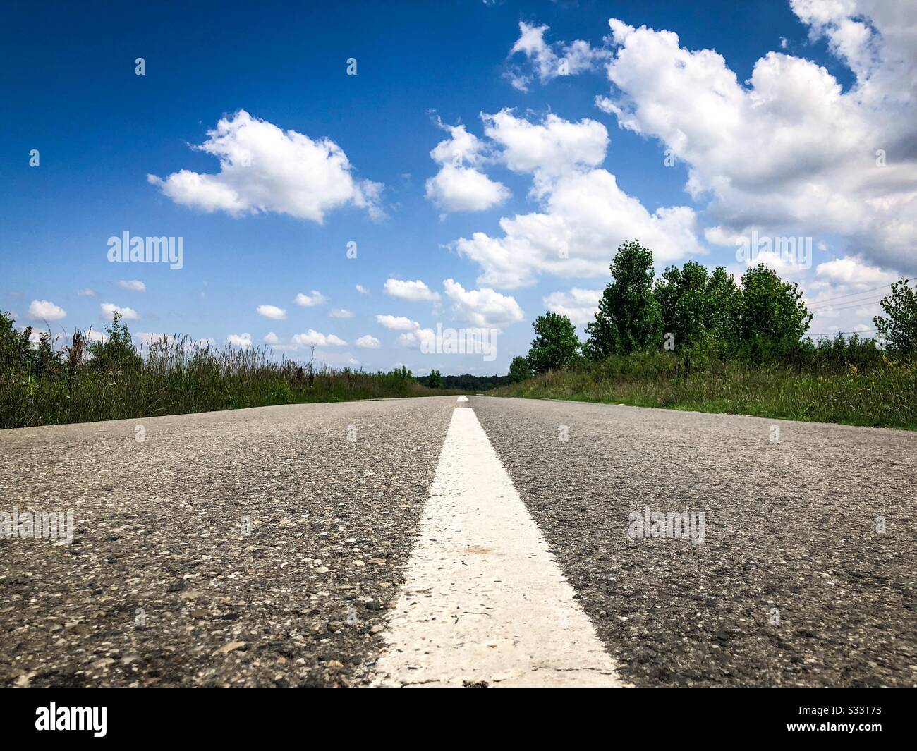 Empty road on a sunny day with white fluffy clouds - Smartphone Captured Stock Image