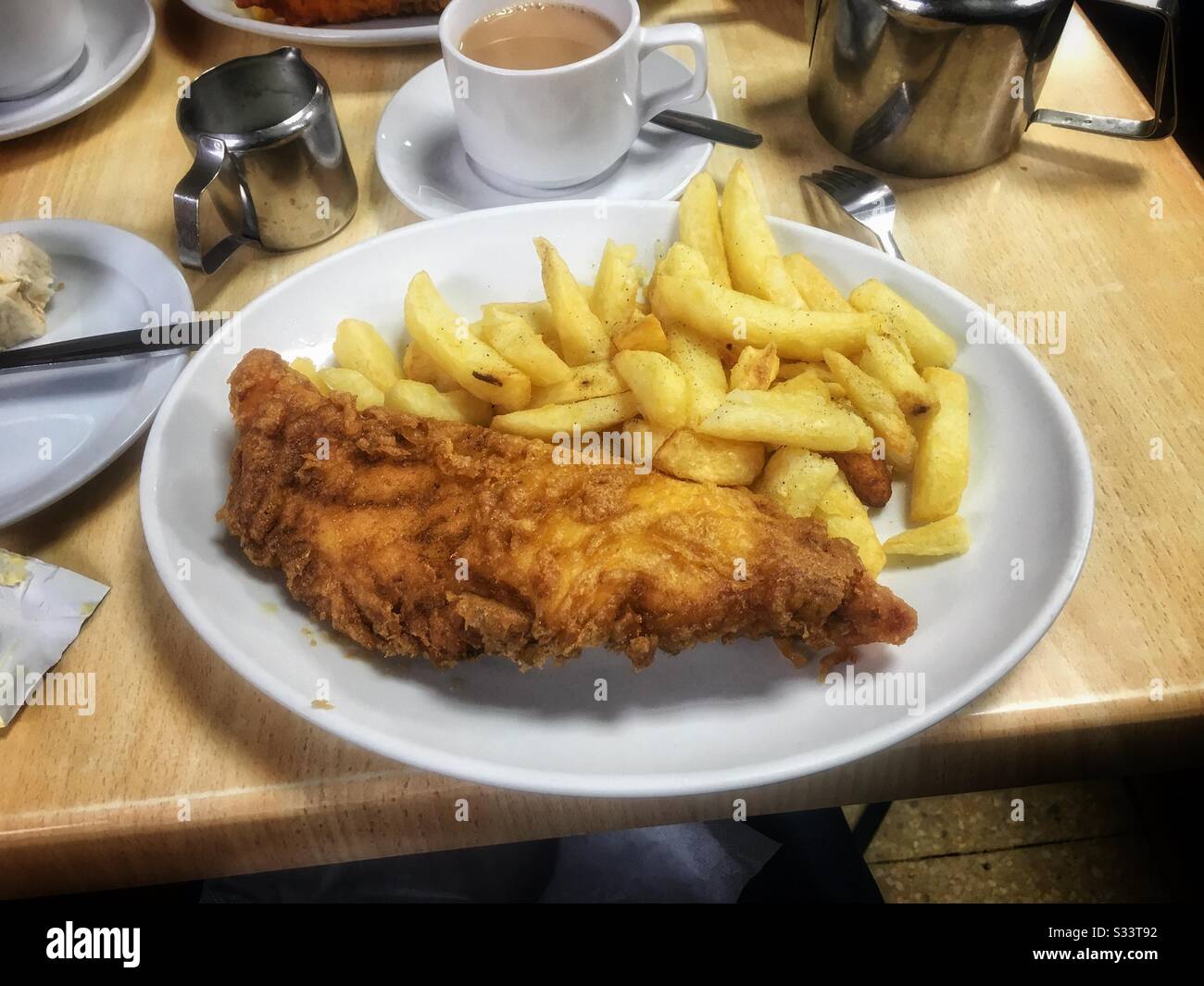 A nice plate of freshly cooked fish and chips with a pot of tea. Stock Photo