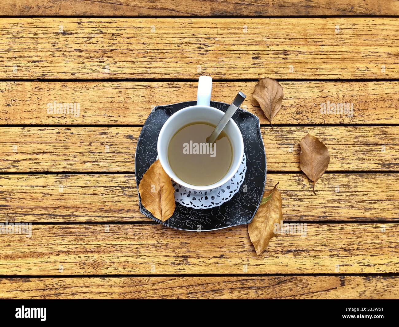 Cup of tea and autumn leaves on rustic wooden table - Smartphone Captured Stock Image