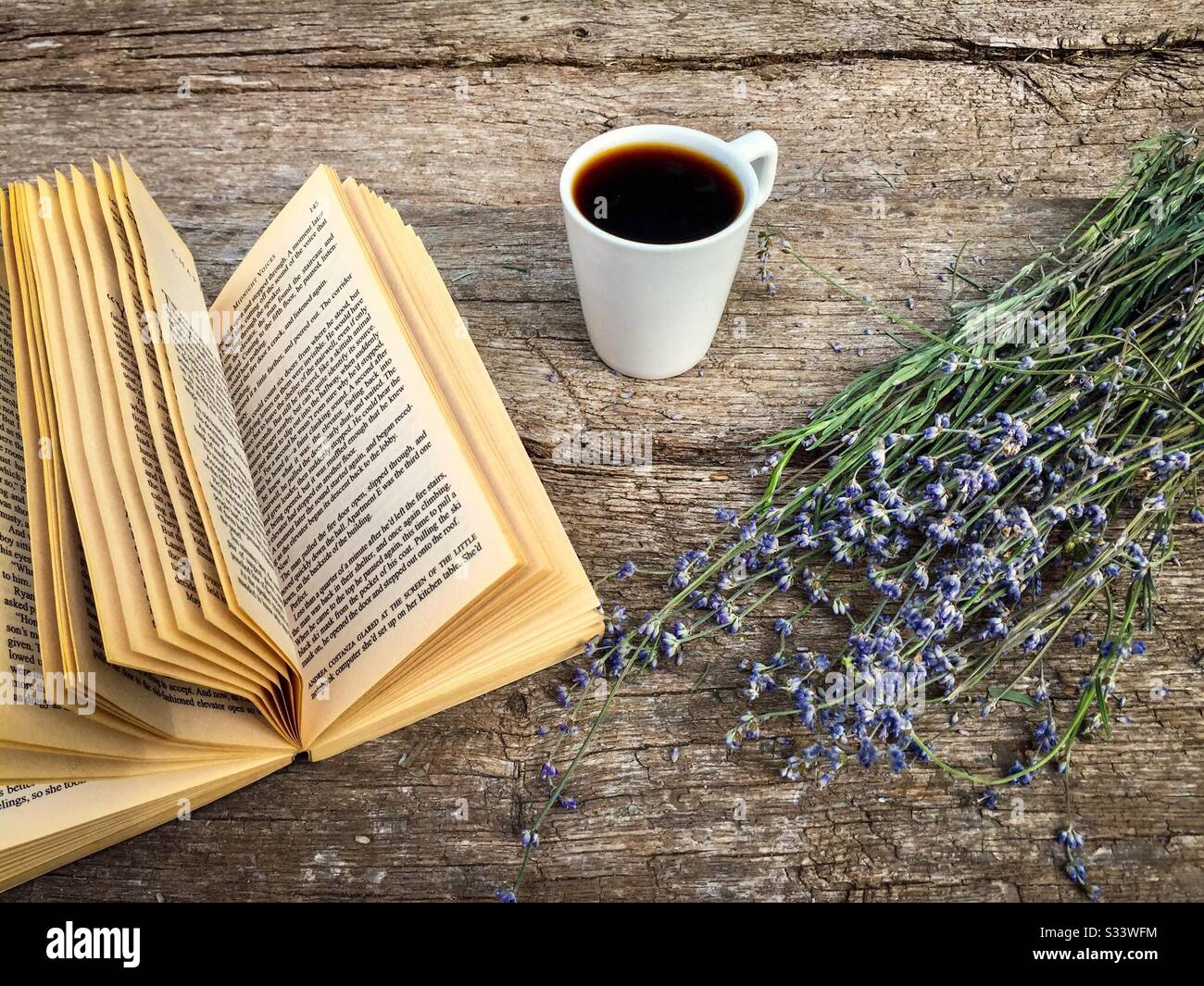 Cup of coffee, a book and lavender flowers on rustic wooden table - Smartphone Captured Stock Image