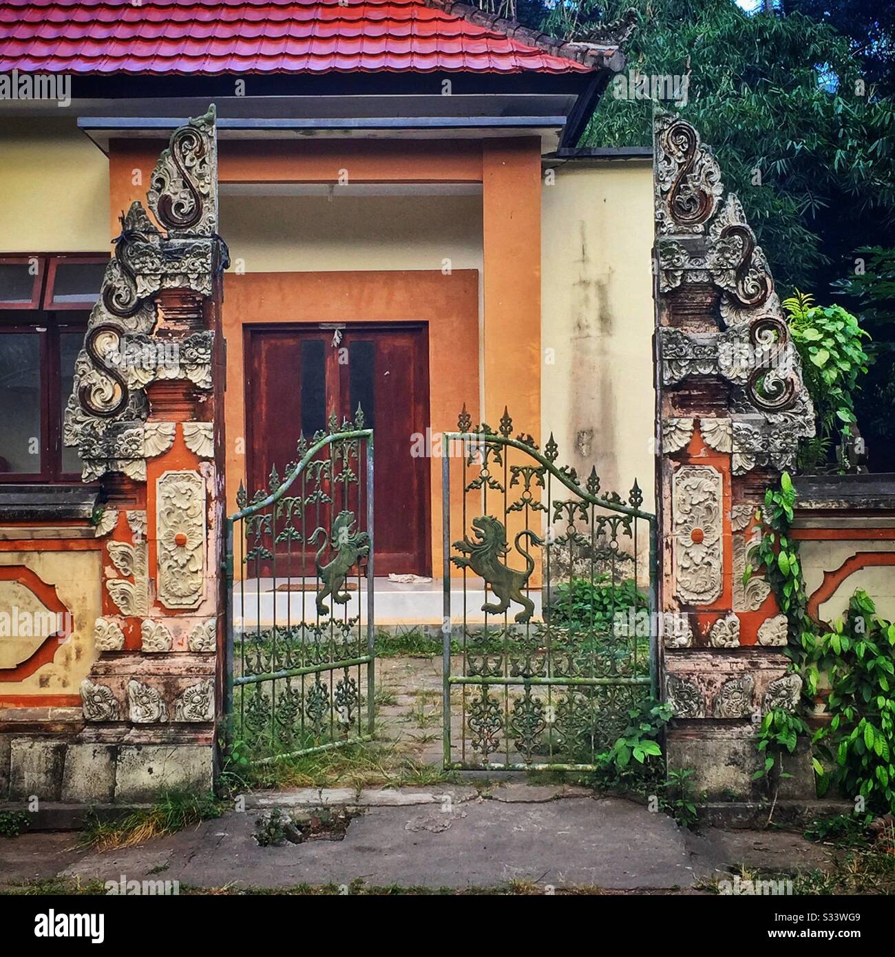 Entance to a modern Balinese house, consisting of a traditional candi bentar, or split gateway, and iron gates with lion motifs, Candidasa, Bali, Indonesia Stock Photo