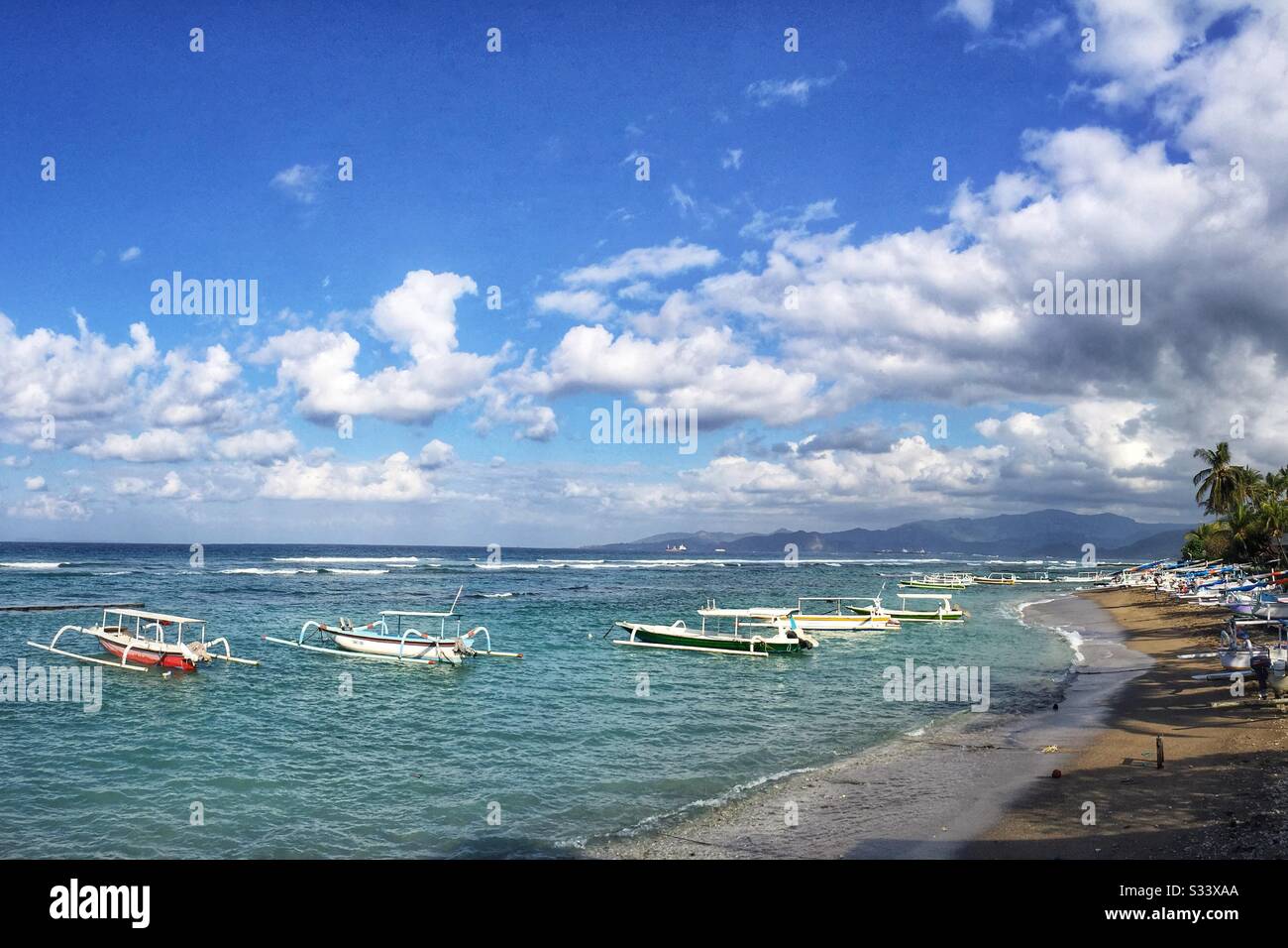Traditional Balinese outrigger fishing boats, also used to ferry tourists on sightseeing, diving or snorkelling trips, Candidasa Beach, Bali, Indonesia - Smartphone Captured Stock Image
