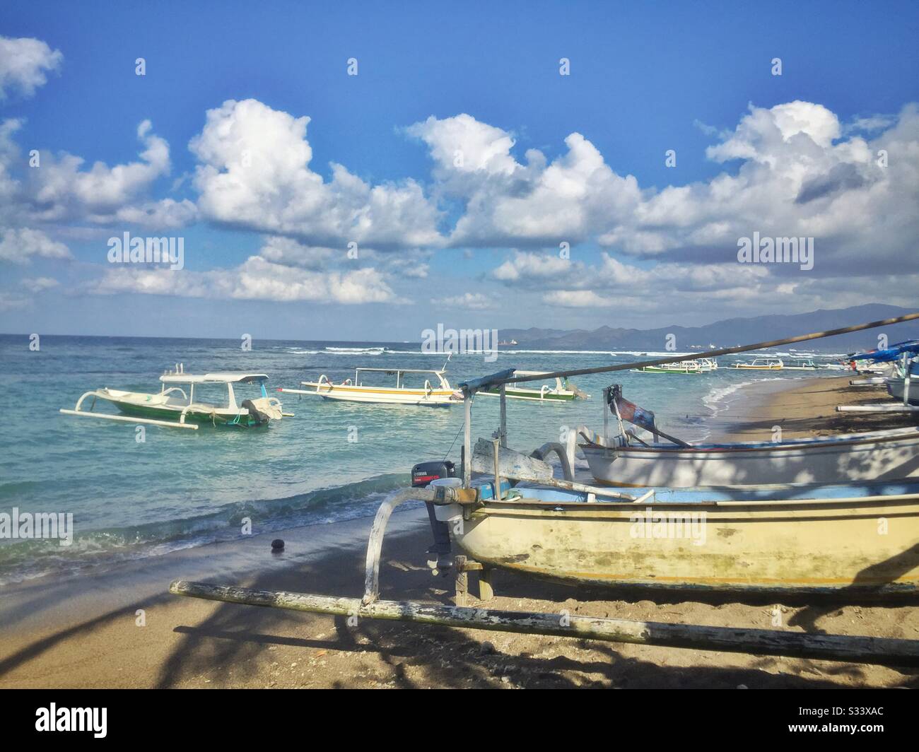 Traditional Balinese outrigger fishing boats, also used to ferry tourists on sightseeing, diving or snorkelling trips, Candidasa Beach, Bali, Indonesia - Smartphone Captured Stock Image