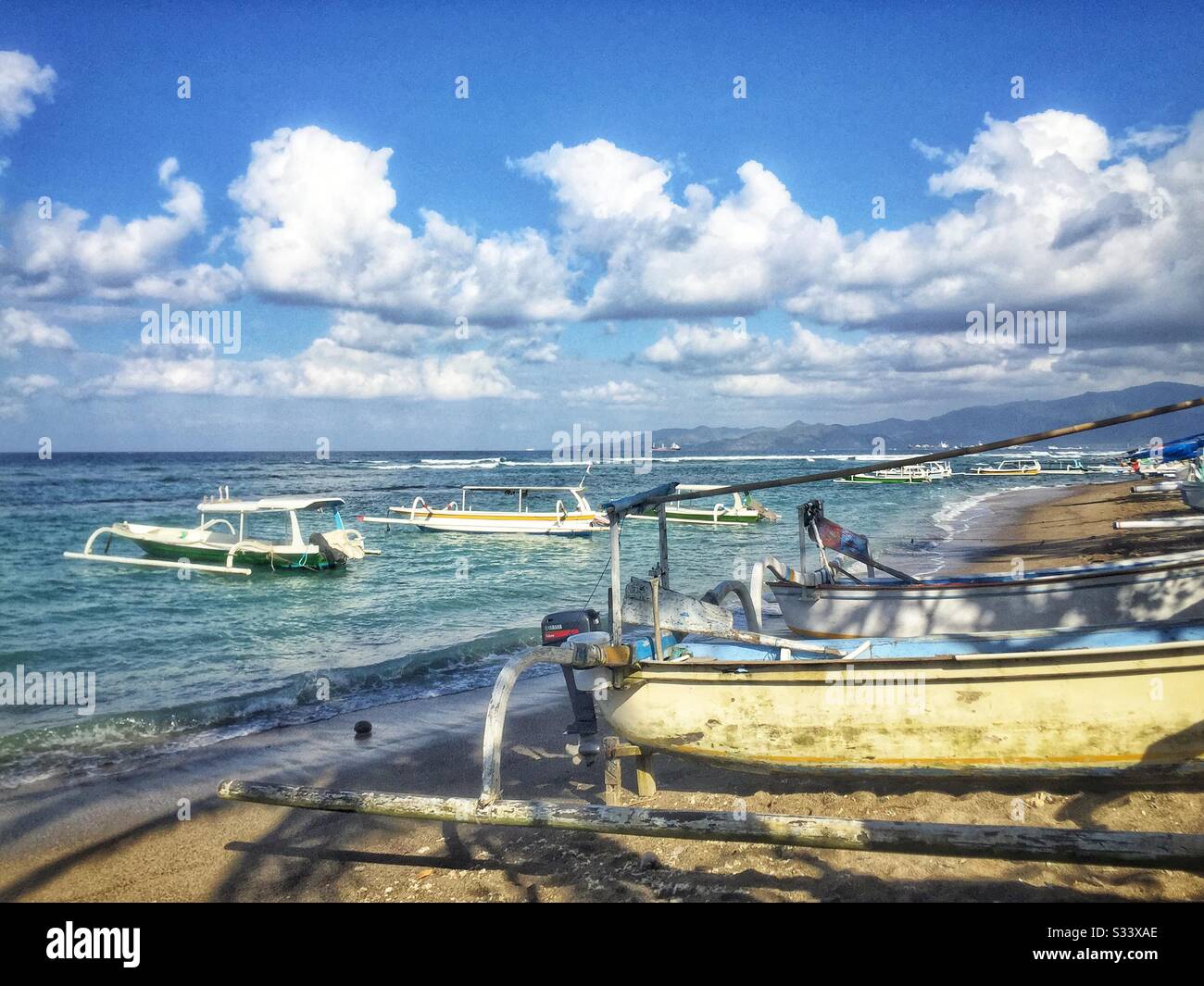 Traditional Balinese outrigger fishing boats, also used to ferry tourists on sightseeing, diving or snorkelling trips, Candidasa Beach, Bali, Indonesia - Smartphone Captured Stock Image