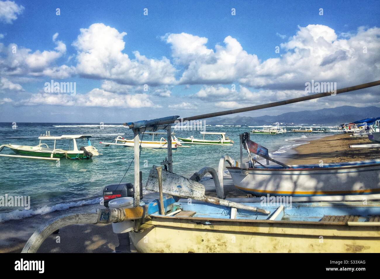 Traditional Balinese outrigger fishing boats, also used to ferry tourists on sightseeing, diving or snorkelling trips, Candidasa Beach, Bali, Indonesia - Smartphone Captured Stock Image