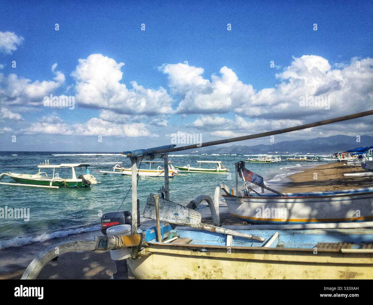 Traditional Balinese outrigger fishing boats, also used to ferry tourists on sightseeing, diving or snorkelling trips, Candidasa Beach, Bali, Indonesia - Smartphone Captured Stock Image