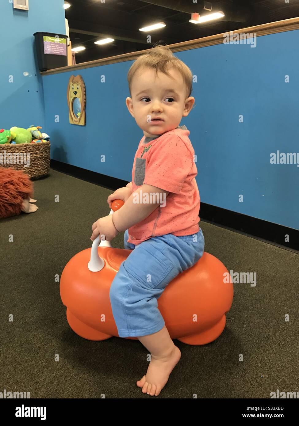 Baby bouncing on the bounce toy. Bear feet. Holding to the toy. Looking.  Inside Stock Photo - Alamy